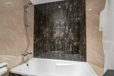 a bathroom with a shower with a black tile wall at Romantic hideaway w breathtaking Burj Khalifa view in Dubai