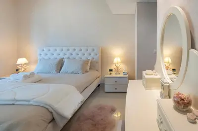 a white bedroom with a large bed and a mirror at Downtown Dubai, Luxury 2 Bed 2 Bath Apartment - Pool, Gym, AirCon, Parking - Views of The Dubai Fountain & Burj Khalifa in Dubai