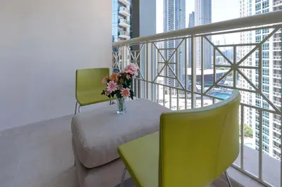 a balcony with two chairs and a vase of flowers at Downtown Dubai, Luxury 2 Bed 2 Bath Apartment - Pool, Gym, AirCon, Parking - Views of The Dubai Fountain & Burj Khalifa in Dubai