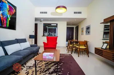 a living room with a blue couch and a red chair at Alashrafia Saray - Wonderful 1BR in Sports City in Dubai