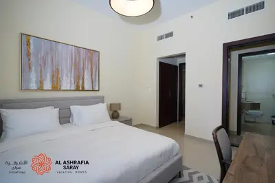 a bedroom with a large white bed and a table at Alashrafia Saray - Wonderful 1BR in Sports City in Dubai