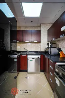a kitchen with wooden cabinets and a stainless steel dishwasher at Alashrafia Saray - Wonderful 1BR in Sports City in Dubai