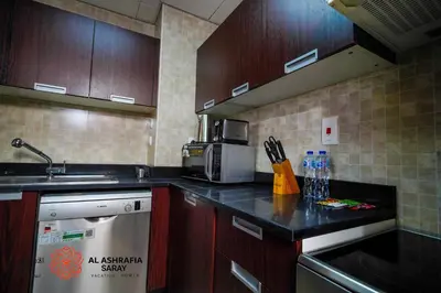 a kitchen with wooden cabinets and a counter top at Alashrafia Saray - Wonderful 1BR in Sports City in Dubai