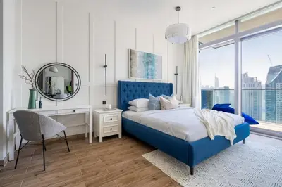 a bedroom with a blue bed and a desk and a mirror at GuestReady - Luxury 1BR | Skyline & Canal View in Dubai