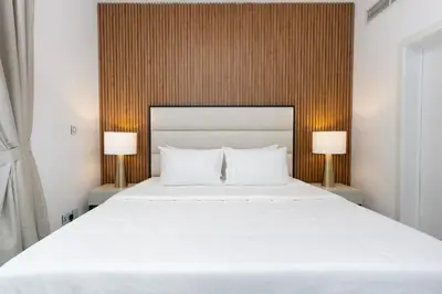 a bedroom with a large white bed with two lamps at Modern Brand New 1BR Holiday Homes at Greens in Dubai