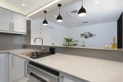 a kitchen with white cabinets and a sink at Modern Brand New 1BR Holiday Homes at Greens in Dubai