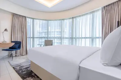 a bedroom with a white bed and a large window at Damac Towers By Paramount Apartments - The S Holiday Homes in Dubai