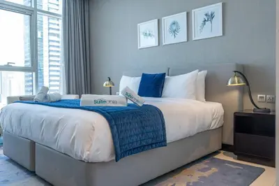 a bedroom with a large bed with blue and white pillows at Sophisticated Business Bay Canal View by Suiteable in Dubai