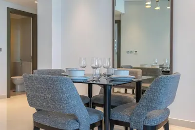 a dining room with a table with chairs and wine glasses at Sophisticated Business Bay Canal View by Suiteable in Dubai