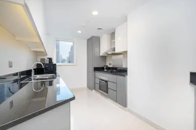 a kitchen with white walls and stainless steel appliances at Sophisticated Business Bay Canal View by Suiteable in Dubai