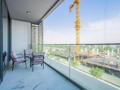 a balcony with chairs and a large window with a crane at Charming Condo With Balcony Near Dubai Hills Park in Dubai