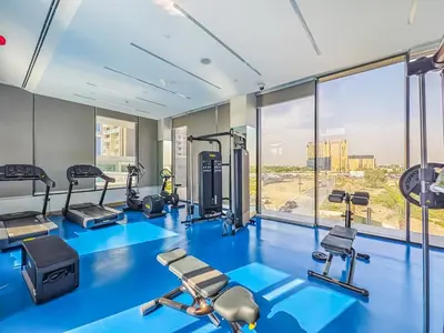 a gym with blue flooring and a large window at Charming Condo With Balcony Near Dubai Hills Park in Dubai