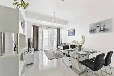 a white living room with a table and chairs at StoneTree - DAMAC Heights 1 BR - Amazing Facilities in Dubai