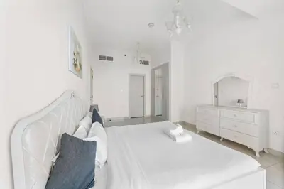 a white bedroom with a white bed and a mirror at StoneTree - DAMAC Heights 1 BR - Amazing Facilities in Dubai