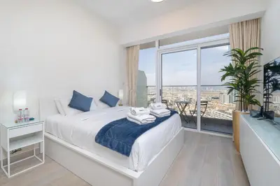 a bedroom with a white bed and a large window at Marina & Downtown Views in Modern Studio - JVC in Dubai