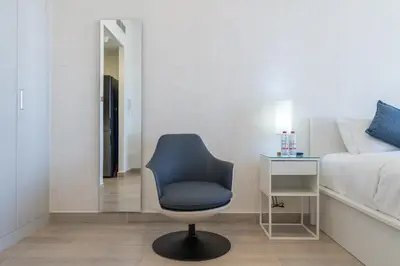 a bedroom with a chair and a bed and a mirror at Marina & Downtown Views in Modern Studio - JVC in Dubai