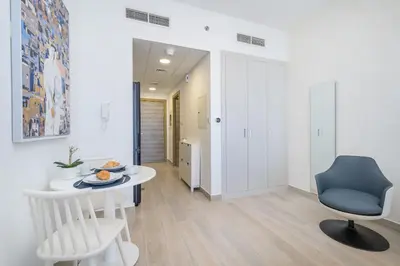 a room with a white table and a blue chair at Marina & Downtown Views in Modern Studio - JVC in Dubai