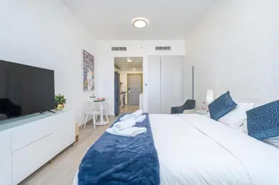 a bedroom with a large white bed and a tv at Marina & Downtown Views in Modern Studio - JVC in Dubai